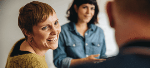 Cheerful woman smiling in conversation with two unidentified people